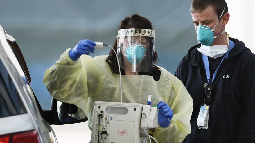 Medical staffers at UNC Hospitals in Chapel Hill, N.C., screen a patient at a drive-thru COVID-19 screening site outside the emergency department. (Scott Sharpe/The News & Observer via AP)