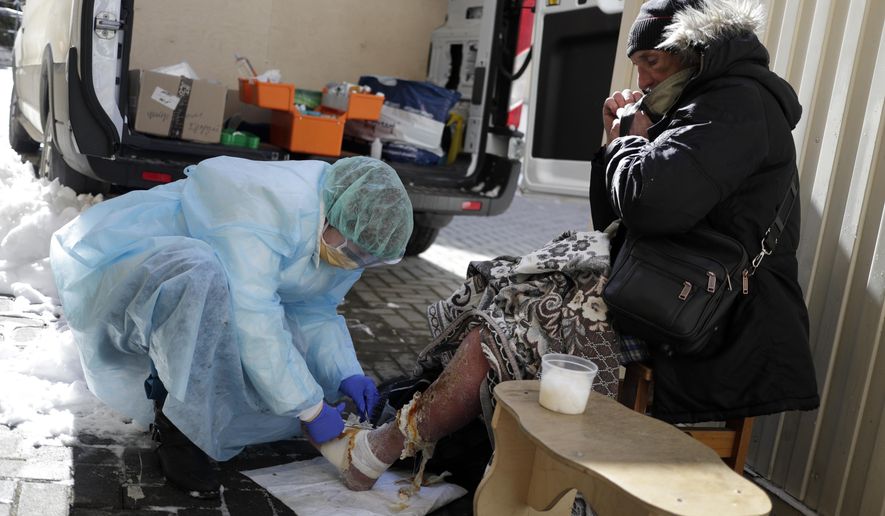 A member of a group of volunteer doctors of the Dom Druzei (Home of Friends) NGO gives a homeless person basic medical help in Moscow, Russia, Wednesday, April 1, 2020. As Moscow goes into lockdown amid the coronavirus pandemic, thousands of homeless people have trouble receiving food, water and shelter as Russia's capital closes nonessential businesses, cafes and parks. The new coronavirus causes mild or moderate symptoms for most people, but for some, especially older adults and people with existing health problems, it can cause more severe illness or death. (AP Photo/Pavel Golovkin)