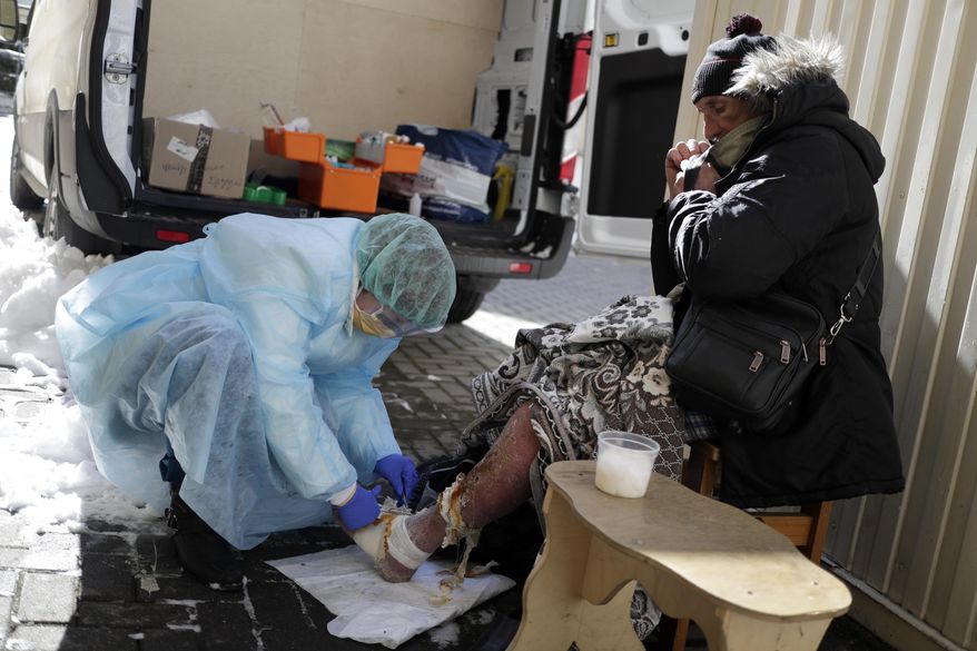 A member of a group of volunteer doctors of the Dom Druzei (Home of Friends) NGO gives a homeless person basic medical help in Moscow, Russia, Wednesday, April 1, 2020. As Moscow goes into lockdown amid the coronavirus pandemic, thousands of homeless people have trouble receiving food, water and shelter as Russia's capital closes nonessential businesses, cafes and parks. The new coronavirus causes mild or moderate symptoms for most people, but for some, especially older adults and people with existing health problems, it can cause more severe illness or death. (AP Photo/Pavel Golovkin)