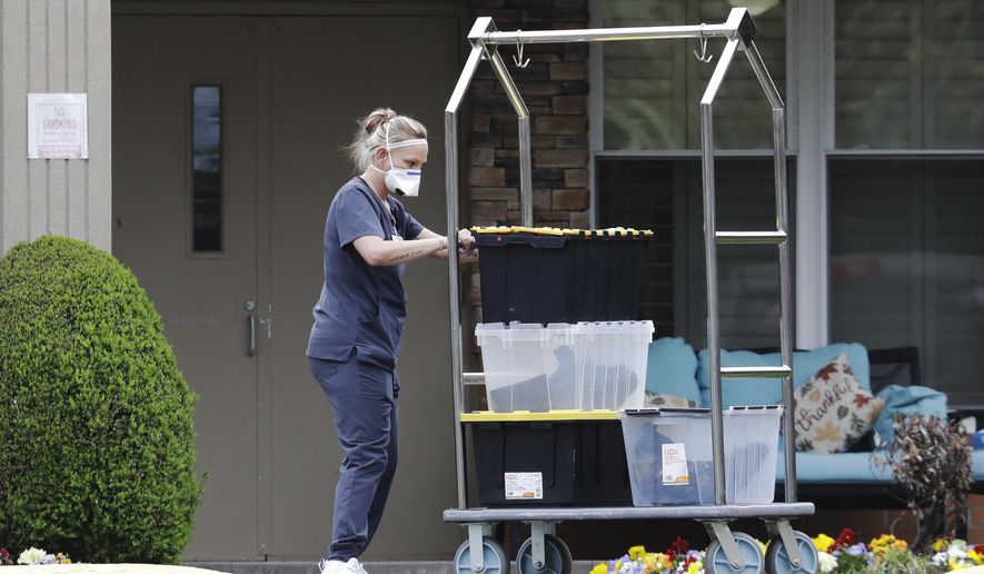 A worker in protective clothing takes materials into the Gallatin Center for Rehabilitation and Healing, Monday, March 30, 2020, in Gallatin, Tenn. Multiple people tested positive for the coronavirus at the facility Friday. Tennessee Gov. Bill Lee issued a statewide "safer-at-home" order on Monday to help stem the state's rapid spread of coronavirus, mandating the closure of all nonessential businesses while urging residents to remain at home whenever possible for the next two weeks. (AP Photo/Mark Humphrey)