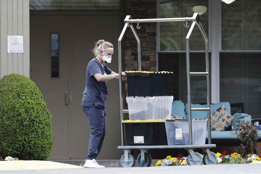 A worker in protective clothing takes materials into the Gallatin Center for Rehabilitation and Healing, Monday, March 30, 2020, in Gallatin, Tenn. Multiple people tested positive for the coronavirus at the facility Friday. Tennessee Gov. Bill Lee issued a statewide "safer-at-home" order on Monday to help stem the state's rapid spread of coronavirus, mandating the closure of all nonessential businesses while urging residents to remain at home whenever possible for the next two weeks. (AP Photo/Mark Humphrey)