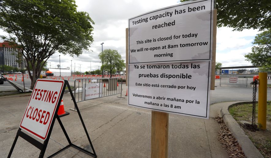 Signs placed outside a barricaded entrance to a coronavirus testing location state the location is closed for the day in Dallas, Tuesday, March 31, 2020. (AP Photo/Tony Gutierrez)