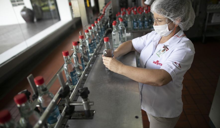 A worker inspects bottles of antiseptic alcohol at the Santa Teresa rum factory in La Victoria, Aragua state, Venezuela, Wednesday, April 1, 2020. Venezuela&#x27;s premier rum distillery and one of Venezuela&#x27;s few private businesses says that most of its production will be for antiseptic alcohol, in an effort to help contain the spread of the new coronavirus. (AP Photo/Ariana Cubillos)