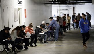 FILE - In this March 13, 2020 file photo, unionized hospitality workers wait in line in a basement garage to apply for unemployment benefits at the Hospitality Training Academy in Los Angeles.  More than 6.6 million Americans applied for unemployment benefits last week, far exceeding a record high set just last week, a sign that layoffs are accelerating in the midst of the coronavirus.   (AP Photo/Marcio Jose Sanchez, File)