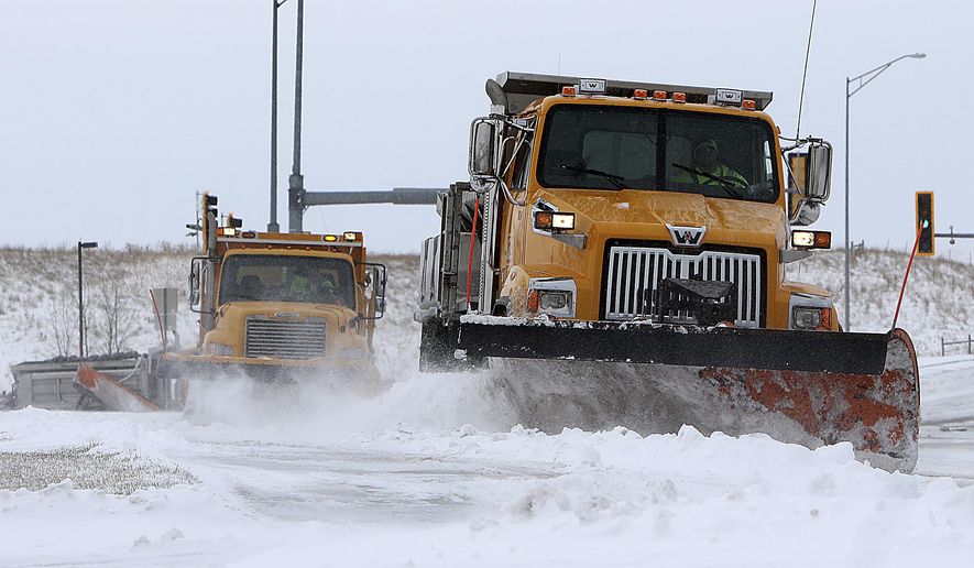 Plows from the City of Rapid City Streets Department work their way along Fifth Street in Rapid City, S.D., Thursday ,April 2, 2020, to clear snow and ice after a winter storm moved into the Black Hills region on Wednesday. (Jeff Easton/Rapid City Journal via AP)