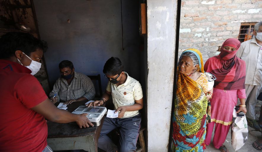 An Impoverished Indians gives his finger print on a biometric machine after purchasing food ration in Prayagraj, India, Thursday, April 2, 2020. India is adding more resources to tackle its increase in coronavirus cases by announcing that private hospitals may be requisitioned to help treat virus patients, and turning railway cars and a motor racing circuit into makeshift quarantine facilities. The steps were taken after a nationwide lockdown announced last week by Prime Minister Narendra Modi led to a mass exodus of migrant workers from cities to their villages, often on foot and without food and water, raising fears that the virus may have reached to the countryside, where health care facilities are limited. (AP Photo/Rajesh Kumar Singh)