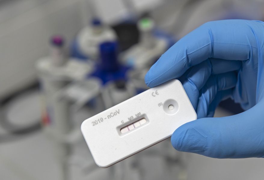 A scientist presents an antibody test for coronavirus in a laboratory of the Leibniz Institute of Photonic Technology (Leibniz IPHT) at the InfectoGnostics research campus in Jena, Germany, Friday, April 3, 2020. An international team of researchers with the participation of the Jena Leibniz Institute of Photonic Technology (Leibniz IPHT) has developed a rapid antibody test for the new coronavirus. By means of a blood sample, the test shows within 10 minutes whether a person is acutely infected with the SARS-CoV-2 virus (IgM antibody) or already immune to it (IgG antibody). (AP Photo/Jens Meyer)