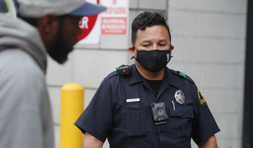 Practicing social distancing amid COVID-19 concerns, Dallas  Police officer R. Salgado looks on while a man speaks in downtown Dallas, Friday, April 3, 2020. New federal guidelines are also expected soon on wearing face masks to help curb the spread of the virus, Trump said recently, adding that the guidance won&#39;t require all Americans to use face coverings. For most people, the coronavirus causes mild or moderate symptoms, such as fever and cough that clear up in two to three weeks. For some, especially older adults and people with existing health problems, it can cause more severe illness, including pneumonia and death. (AP Photo/LM Otero)