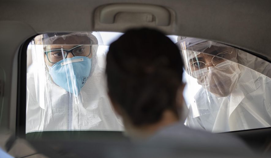 Medical workers wearing protective gear peer into a car checking if commuters have COVID-19 symptoms, in Guarulhos on the outskirts of Sao Paulo, Brazil, Monday, March 30, 2020. President Jair Bolsonaro has stuck with his contention that concern about the new coronavirus is overblown, and accused Brazilian media of trying to stoke nationwide hysteria. (AP Photo/Andre Penner)