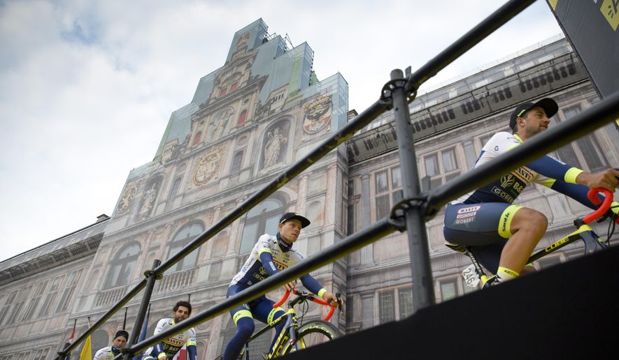 FILE - In this Sunday, April 7, 2019 file photo, Belgium's Ludwig De Winter of the Wanty-Gobert team, right, leads the rest of his team up to the podium during the team presentations for the Tour of Flanders cycling race in Antwerp, Belgium. One of the five so-called “Monuments” _ the five most prestigious one-day races in cycling _ the “Ronde" has been scrapped from this season's calendar because of the outbreak of the coronavirus. All schools in the country have been shut down, only a handful of businesses remain open for essential needs while riding bikes in large groups has been forbidden. To keep the festive event alive, race organizers Flanders Classics will host a “lockdown edition" of the race on Sunday, April 5, 2020 with pro riders tackling the punishing Oude Kwaremont and Paterberg climbs from the comfort of their houses, on home trainers. (AP Photo/Virginia Mayo, File)