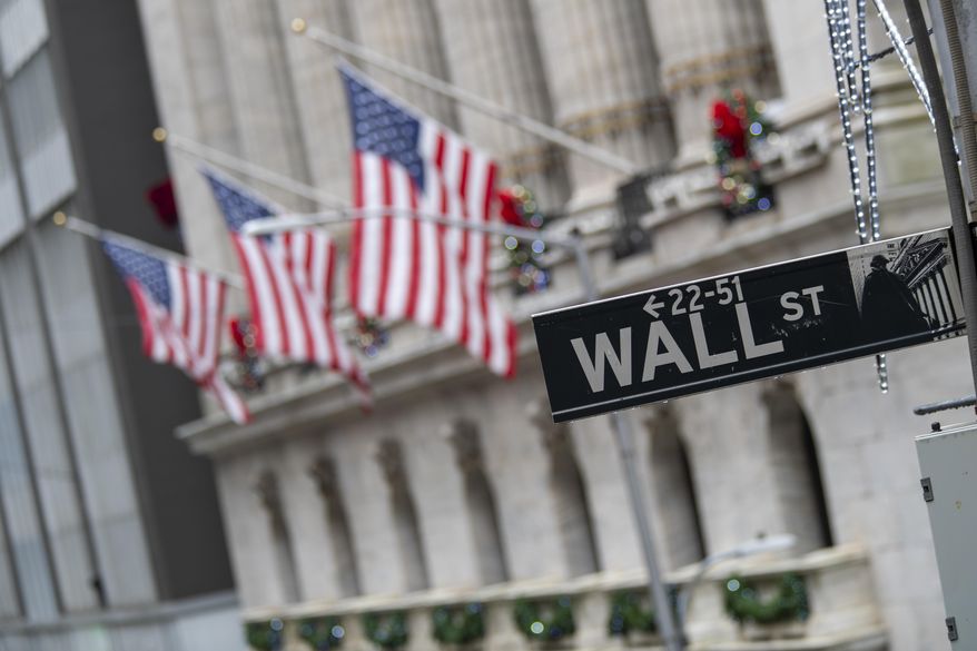 FILE - In this Jan. 3, 2020 file photo, the Wall St. street sign is framed by U.S. flags flying outside the New York Stock Exchange in New York. Global stocks are down, Friday, April 3, after the U.S. government said employers cut 701,000 jobs in March as they shut down or sharply curtailed business due to the coronavirus outbreak. (AP Photo/Mary Altaffer, File)