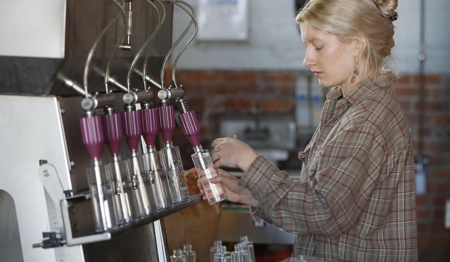 Two James Spirits employee Allie Sieracki fills bottles with hand sanitizer being produced at the distillery, Friday, April 3, 2020, in Detroit. After a revision to FDA regulations on the manufacture of hand sanitizer, bars and alcohol producers are permitted to distribute the product. The distillery is one of many across the country which have shifted their production away from spirits and starting to make hand sanitizer to help ease the coronavirus-induced shortage of the product. (AP Photo/Carlos Osorio)