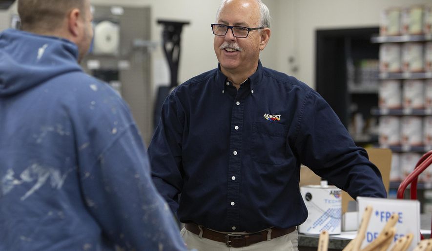 In this Wednesday, March 25, 2020 photo, Kevin Abbott talks with customer John McCoy on, at Abbott Paint and Carpet in St. Paul, Minn,. Abbott says that his store has been busy as people take on home projects while they stay at home amid the COVID-19 pandemic. (Christine T. Nguyen/Minnesota Public Radio via AP)