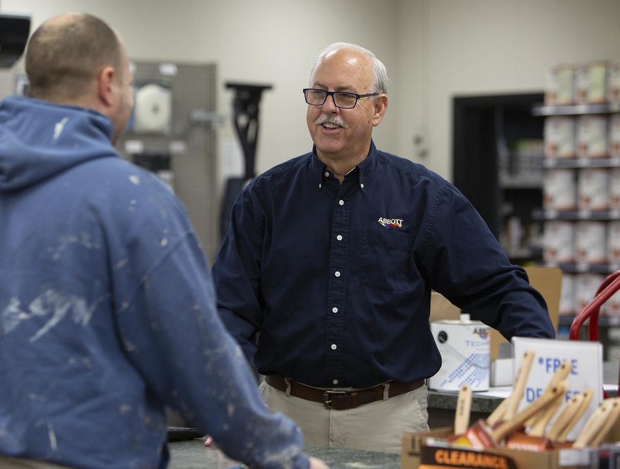 In this Wednesday, March 25, 2020 photo, Kevin Abbott talks with customer John McCoy on, at Abbott Paint and Carpet in St. Paul, Minn,. Abbott says that his store has been busy as people take on home projects while they stay at home amid the COVID-19 pandemic. (Christine T. Nguyen/Minnesota Public Radio via AP)