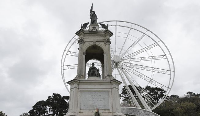 In this Saturday, March 28, 2020, file photo, Eduardo Vernier wears a mask while sitting under the Francis Scott Key monument at Golden Gate Park in San Francisco, amid the coronavirus outbreak. At rear is the SkyStar Observation Wheel. Golden Gate Park turned 150 on Saturday, April 4. To mark this historic occasion, a virtual concert series is being launched that will bring some of the past outdoor concerts and performances held in the park to people everywhere to enjoy for free. (AP Photo/Jeff Chiu) **FILE**