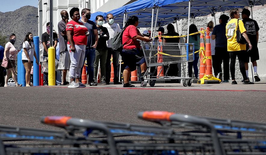 Some people wearing face masks wait in line to shop Saturday, April 4, 2020, in Tempe, Ariz. Honeywell announced that it is adding manufacturing capabilities in Phoenix to produce N95 face masks in support of the government's response to the novel coronavirus The company's Phoenix expansion will allow Honeywell to produce more than 20 million N95 disposable masks monthly to combat COVID-19 in the U.S. The new coronavirus causes mild or moderate symptoms for most people, but for some, especially older adults and people with existing health problems, it can cause more severe illness or death. (AP Photo/Matt York)