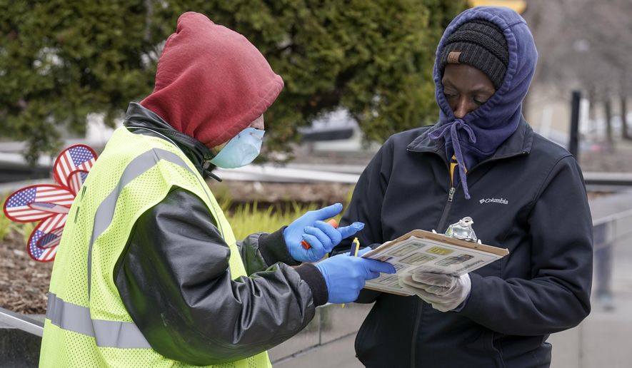 A worker helps voter outside the Frank P. Zeidler Municipal Building Monday March 30, 2020, in Milwaukee. The city is now allowing drive up early voting for the state's April 7 election. (AP Photo/Morry Gash)