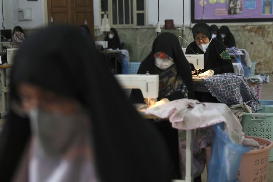 Volunteer women wearing face masks and gloves to curb the spread of the new coronavirus sew bed sheets for hospitals, in a mosque in southern Tehran, Iran, Sunday, April 5, 2020. Iran is battling the worst new coronavirus outbreak in the Mideast. (AP Photo/Vahid Salemi)