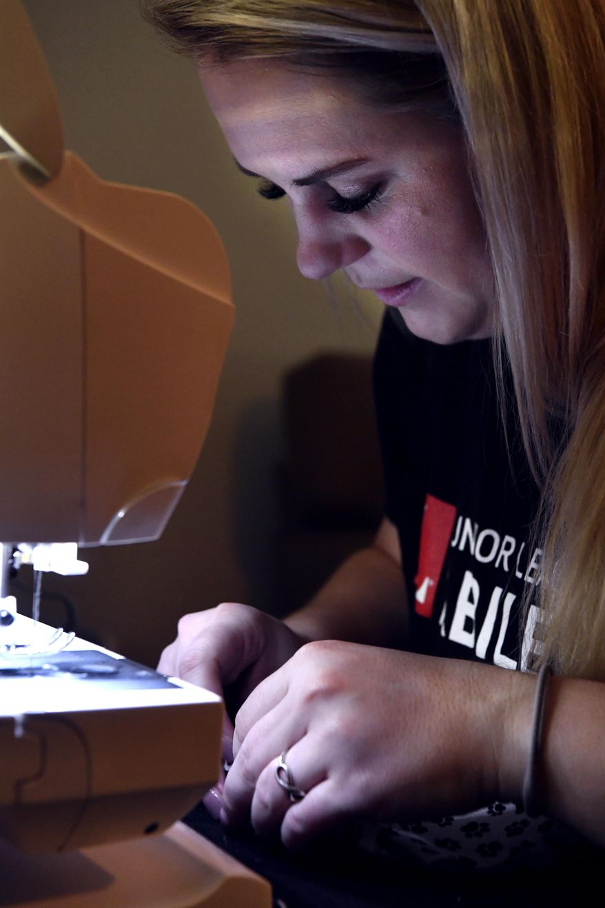 Alex Swize looks at her work as she sews a face mask at her home in Abilene, Texas Saturday March 28, 2020. She received this sewing machine from her grandmother. (Ronald W. Erdrich/The Abilene Reporter-News via AP)