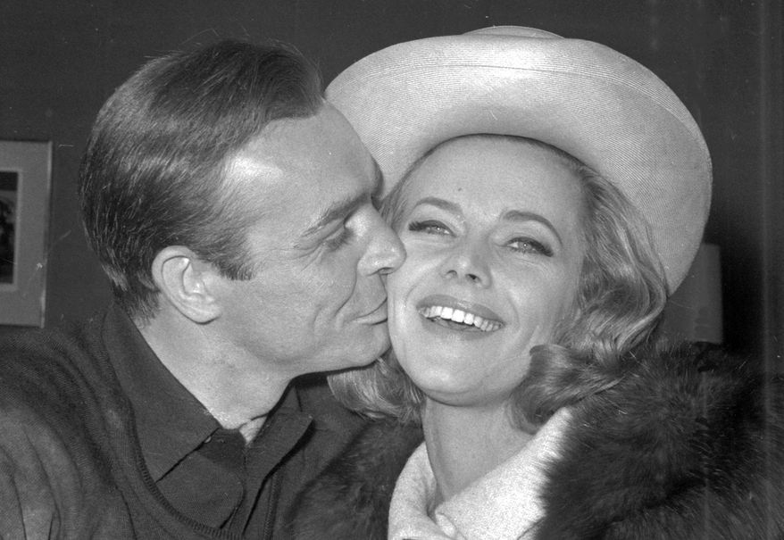 FILE - In this B/W file photo dated March 25, 1964, British actor Sean Connery kisses actress Honor Blackman during a party at Pinewood Film Studios, in Iver Heath, England. Blackman, the actor best-known for playing Bond girl Pussy Galore, hasdied of natural causes unrelated to coronavirus, aged 94, according to an announcement Monday April 6, 2020. (AP Photo, FILE)
