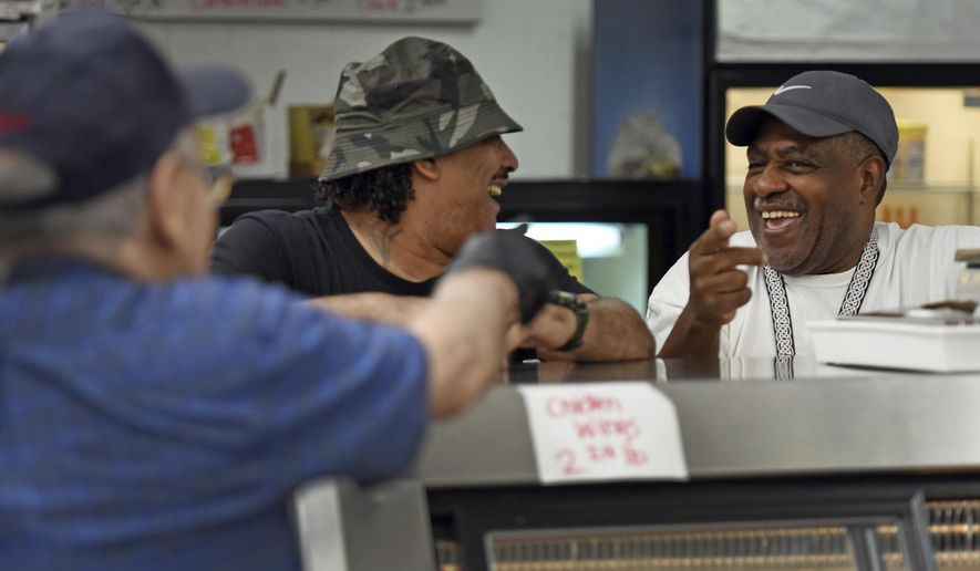 In this Saturday, March 28, 2020 photo, Edward Abbott , right, and Reggie Cannady joke with Ogburn Station Meat Market owner Herman Barker in Winston-Salem, N.C. While many of the regional and national chain supermarkets have been low or out of meat because of panic shopping in light of coronavirus concerns, Ogburn Station Meat Market has been fully stocked and doing a brisk business. (Walt Unks/The Winston-Salem Journal via AP)