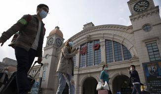 Travelers with their luggage walk past the Hankou railway station on the eve of its resuming outbound traffic in Wuhan in central China&#39;s Hubei province on Tuesday, April 7, 2020. Starting Wednesday, residents of Wuhan will be allowed to once again travel in and out of the sprawling city where the coronavirus pandemic began, ending an 11-week lockdown. (AP Photo/Ng Han Guan)