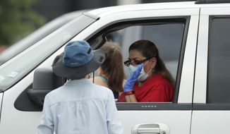 A woman sits in her car as workers and volunteers load her car with food at a San Antonio Food Bank drive-through distribution in San Antonio, Tuesday, April 7, 2020. The new coronavirus causes mild or moderate symptoms for most people, but for some, especially older adults and people with existing health problems, it can cause more severe illness or death. (AP Photo/Eric Gay) **FILE**