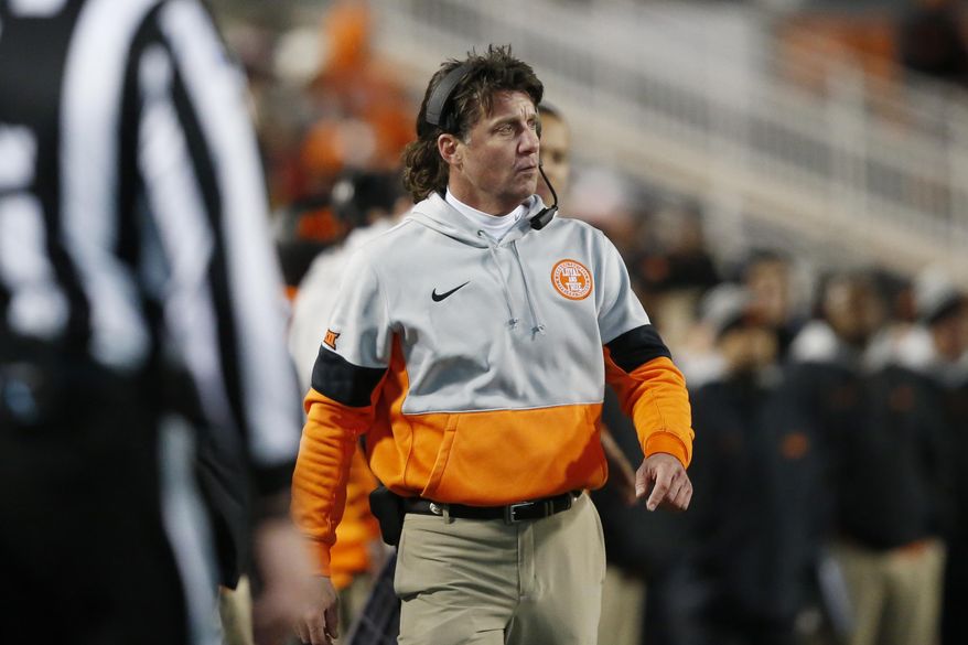 In this Nov. 30, 2019 file photo Oklahoma State head coach Mike Gundy walks on the sidelines during an NCAA college football game against Oklahoma in Stillwater, Okla. Gundy said Tuesday, April 7, 2020 he hopes to have his team return to its facilities on May 1, a proposed timetable that would defy federal social-distancing guidelines and was quickly disputed by the university and its athletic director. (AP Photo/Sue Ogrocki) **FILE**