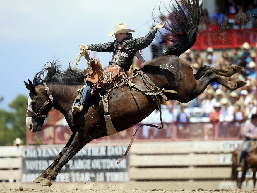 FILE - In this July 29, 2018, file photo, Brody Cress, of Hillsdale, Wyo. competes in the saddle bronc event during Championship Sunday of the 122nd annual Cheyenne Frontier Days Rodeo at Frontier Park Arena in Cheyenne, Wyo. When Augusta comes up, one instantly thinks of the Masters. If Omaha is mentioned, it’s often in the same breath with the College World Series. For those cities and others like them _ from Williamsport to Oklahoma City to Cheyenne _ the shutdown caused by the coronavirus pandemic is an especially wrenching blow. (Blaine McCartney/The Wyoming Tribune Eagle via AP, File)