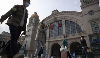 Travelers with their luggage walk past the Hankou railway station on the eve of its resuming outbound traffic in Wuhan in central China&#39;s Hubei province on Tuesday, April 7, 2020. Starting Wednesday, residents of Wuhan will be allowed to once again travel in and out of the sprawling city where the coronavirus pandemic began, ending an 11-week lockdown. (AP Photo/Ng Han Guan)