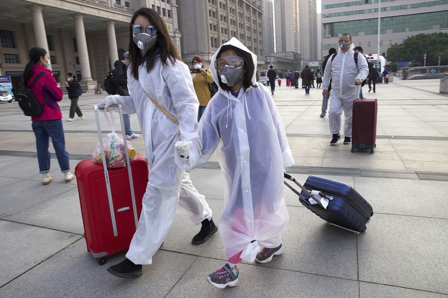 Passengers wearing face masks and rain coats to protect against the spread of new coronavirus walk outside of Hankou train station after of the resumption of train services in Wuhan in central China&#39;s Hubei Province, Wednesday, April 8, 2020. After 11 weeks of lockdown, the first train departed Wednesday morning from a re-opened Wuhan, the origin point for the coronavirus pandemic, as residents once again were allowed to travel in and out of the sprawling central Chinese city. (AP Photo/Ng Han Guan)