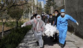FILE - In this Monday, March 30, 2020 file photo, people carry the body of a victim who died after being infected with the new coronavirus at a cemetery just outside Tehran, Iran. Across the Middle East and parts of South Asia, bereaved families have faced traumatic restrictions on burying their dead amid the pandemic. Religion and customs that require speedy burials in the largely Muslim region have clashed with fears of COVID-19 contagion and government-mandated lockdowns. (AP Photo/Ebrahim Noroozi, File)