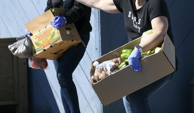 Dolly Sherman, right, prepares to place produce in the trunk of a car during the Conneaut Human Resources Center&#x27;s monthly produce distribution on on Monday April 6, 2020, morning in Conneaut, Ohio. (Warren Dillaway/The Star-Beacon via AP)