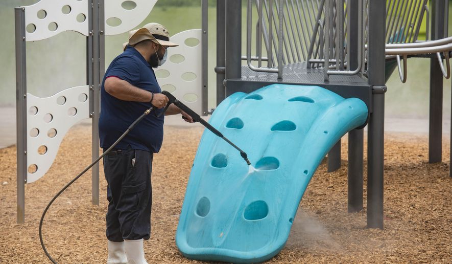 Sparkling Clean Professional Exterior Cleaning & Restoration owner Carlos Sanchez uses a sanitizing solution on the Woldert Park playground in Tyler, Texas on Friday, April 3, 2020. Sanchez offered to clean the city's playgrounds for free to support the community during the coronavirus pandemic. (Sarah A. Miller/Tyler Morning Telegraph via AP)