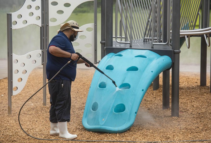 Sparkling Clean Professional Exterior Cleaning & Restoration owner Carlos Sanchez uses a sanitizing solution on the Woldert Park playground in Tyler, Texas on Friday, April 3, 2020. Sanchez offered to clean the city's playgrounds for free to support the community during the coronavirus pandemic. (Sarah A. Miller/Tyler Morning Telegraph via AP)
