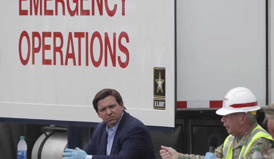 Florida Gov. Ron DeSantis, center, listens as Chief of Engineers and Commanding General of the U.S. Army Corps of Engineers Lt. Gen. Todd T. Semonite, right, speaks during a news conference in front of a U.S. Army Corps of Engineers mobile command center at the Miami Beach Convention Center, Wednesday, April 8, 2020, in Miami Beach, Fla. The Corps of Engineers will transform the newly renovated facility into a hospital by April 27, news outlets reported Tuesday. (AP Photo/Wilfredo Lee)