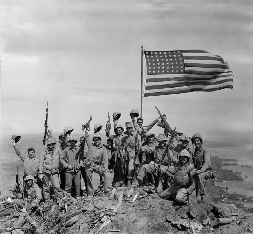 U.S. Marines of the 28th Regiment, fifth division, cheer and hold up their rifles after raising the American flag atop Mount Suribachi on Iwo Jima, a volcanic Japanese island, on Feb. 23, 1945 during World War II.  (AP Photo/Joe Rosenthal)