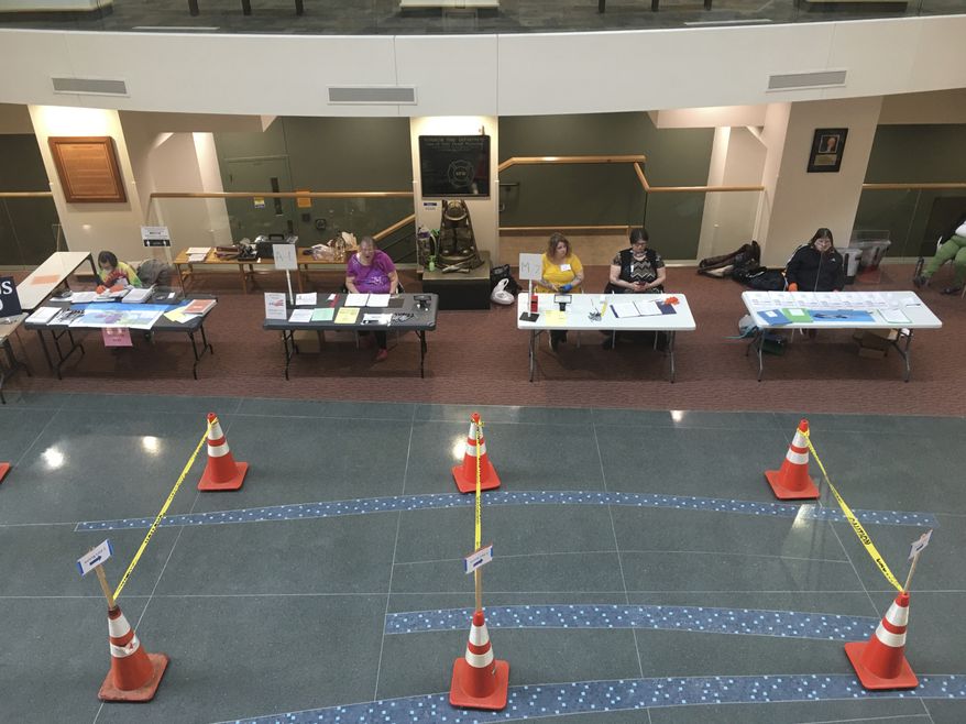 FILE - In this April 7, 2020, file photo poll workers used caution tape and pylons to set up aisles to help maintain proper social distancing at a polling place set up at the Government Center in Superior, Wis., as voters, ignoring a stay-at-home order over the coronavirus threat, cast ballots in the state's presidential primary election. A partisan fight over voting in Wisconsin was the first issue linked to the coronavirus to make it to the Supreme Court. (Dan Kraker/Minnesota Public Radio via AP, File)