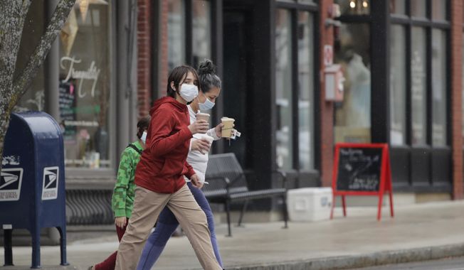 A family, wearing masks due to the virus outbreak, carry drinks as they walk through the empty streets of the village of Exeter, N.H., Thursday, April 9, 2020. (AP Photo/Charles Krupa)
