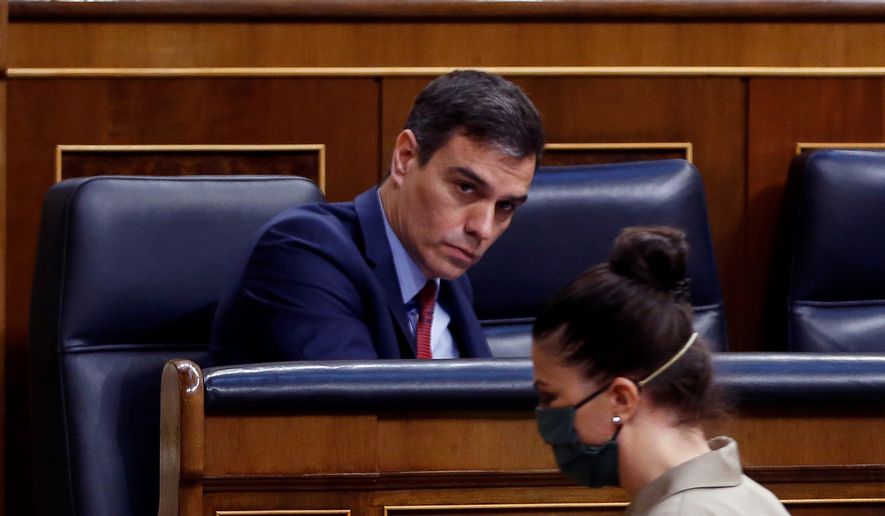 Spain's Prime Minister, Pedro Sanchez looks at far-right Vox party's deputy Macarena Olona wearing a mask to protect against coronavirus, during the opening of a parliamentary session in Madrid, Spain, Thursday, April 9, 2020. Sanchez acknowledged that Spain's government, and its regions which administer health services, were caught off guard by the crisis and left its hospitals woefully short on critical supplies, including virus tests and protective clothing for medical workers. (Mariscal, Pool Photo via AP)