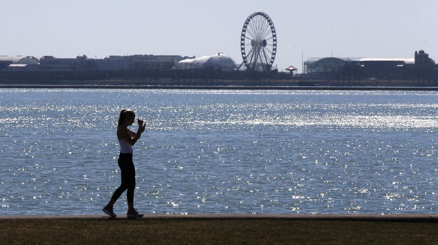FILE - In this March 24, 2017 file photo, a lone woman walks the trail along Lake Michigan at Chicago&#39; North Avenue beach. Additional funds provided by Congress for Great Lakes environmental improvements will be used to quicken cleanups of highly toxic sites and step up work on other longstanding forms of pollution, federal officials said Thursday, April, 9, 2020. (AP Photo/Charles Rex Arbogast, File)