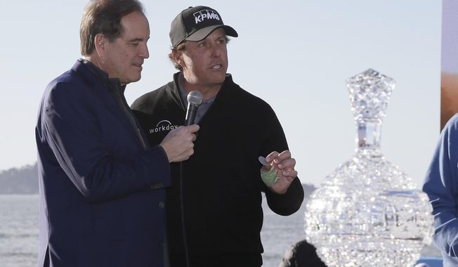 FILE - In this Monday, Feb. 11, 2019, file photo, while being interviewed by broadcaster Jim Nantz, left, Phil Mickelson holds up a silver dollar that belonged to his grandfather during an awards ceremony on the 18th green of the Pebble Beach Golf Links after winning the AT&amp;amp;T Pebble Beach Pro-Am golf tournament, in Pebble Beach, Calif. Nantz has worked the Final Four and Masters for the last 34 years and is missing them in 2020 because of the new coronavirus pandemic. (AP Photo/Eric Risberg, File)