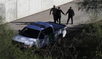 In this Nov. 16, 2016, file photo, a U.S. Customs and Border Patrol agent walks with suspected immigrants caught entering the country illegally along the Rio Grande in Hidalgo, Texas. The Trump administration has quietly shut down the nation&#39;s asylum system for the first time in decades amid coronavirus concerns, largely because holding people in custody is considered too dangerous. (AP Photo/Eric Gay, File)