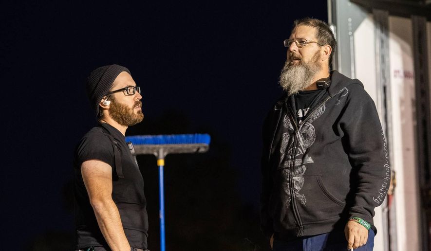 In this Oct. 2019 photo Guitar tech Jon "LJ" Vishnevsky, left, and audio engineer Mike Babcock talk while working at the Exit 111 Festival in Manchester, Tenn. This year, Vishnevsky was touring with the rock band Alter Bridge until March when suddenly the 32-year-old was out of a job as the band and countless others canceled spring shows because of the coronavirus pandemic. Vishnevsky, of Denver, said he applied for unemployment on March 20 and as of Wednesday, April 8, 2020, was still waiting to learn if it would be approved. (Ernest Falconer via AP)