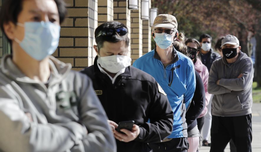 Customers wear a variety of protective masks as they wait some six-feet apart to enter a Trader Joe's store, where the number of customers allowed inside at any one time was limited because of the coronavirus outbreak, Wednesday, April 8, 2020, in Seattle. (AP Photo/Elaine Thompson)
