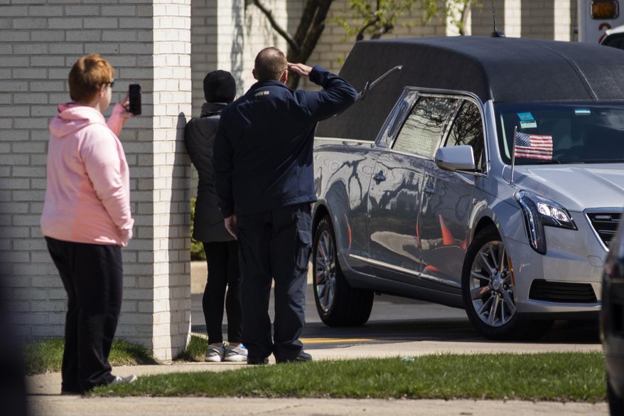 A man salutes as the hearse carrying Chicago Police Officer Officer Marco DiFranco leaves Cumberland Funeral Chapels Thursday, April 9, 2020 in Norridge, Ill. DiFranco, 50, died April 2 from complications due to COVID-19, making him the first Chicago police officer to lose his life to the coronavirus. (Ashlee Rezin Garcia/Chicago Sun-Times via AP)