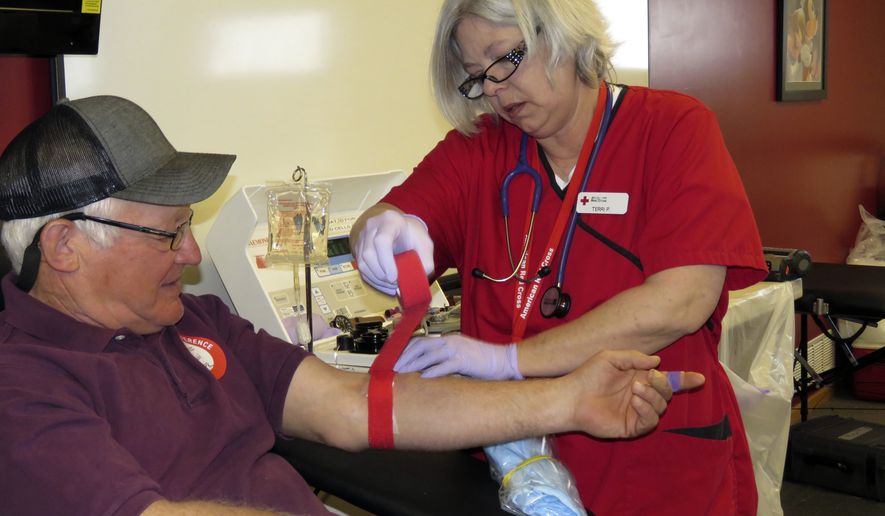 In this Monday, April 6, 2020, photo, phlebotomist Terri Podsobinski, of Maywood, wraps the arm of Ron Bock of Ravenna, in Kearney, Neb. Bock donates &quot;double reds,&quot; which are two units of red cells in one donation. (Lori Potter/Kearney Hub via AP)
