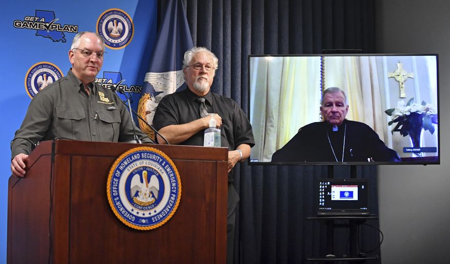 Louisiana Gov. John Bel Edwards, left, flanked by a sign language interpreter, speaks with New Orleans Archbishop Gregory Aymond via conference call on Friday, April 10, 2020, in Baton Rouge, La. Aymond is recovering from COVID-19. (Hilary Scheinuk/The Advocate via AP)