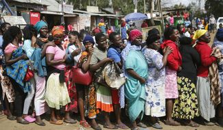 Women queue for a planned distribution of food for those suffering under Kenya&#39;s coronavirus-related movement restrictions, before the crowd pushed through a gate and created a stampede, causing police to fire tear gas and leaving several injured, at a district office in the Kibera slum, or informal settlement, of Nairobi, Kenya, Friday, April 10, 2020. (AP Photo/Brian Inganga)