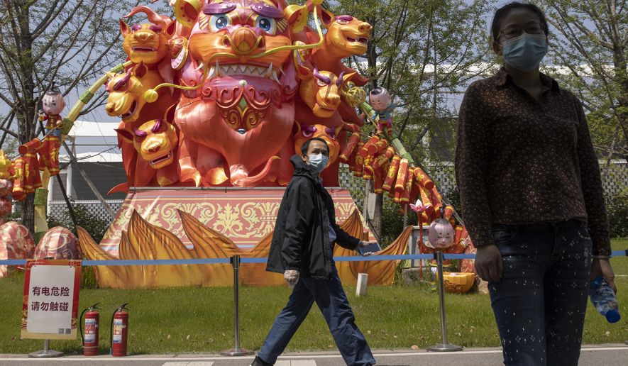 Residents wearing masks against the coronavirus walk past lantern sculptures at a park in Wuhan in central China's Hubei province on Thursday, April 9, 2020. Chinese authorities ended the lockdown of Wuhan on Wednesday, allowing people to move about and leave the city for the first time in 76 days. (AP Photo/Ng Han Guan)